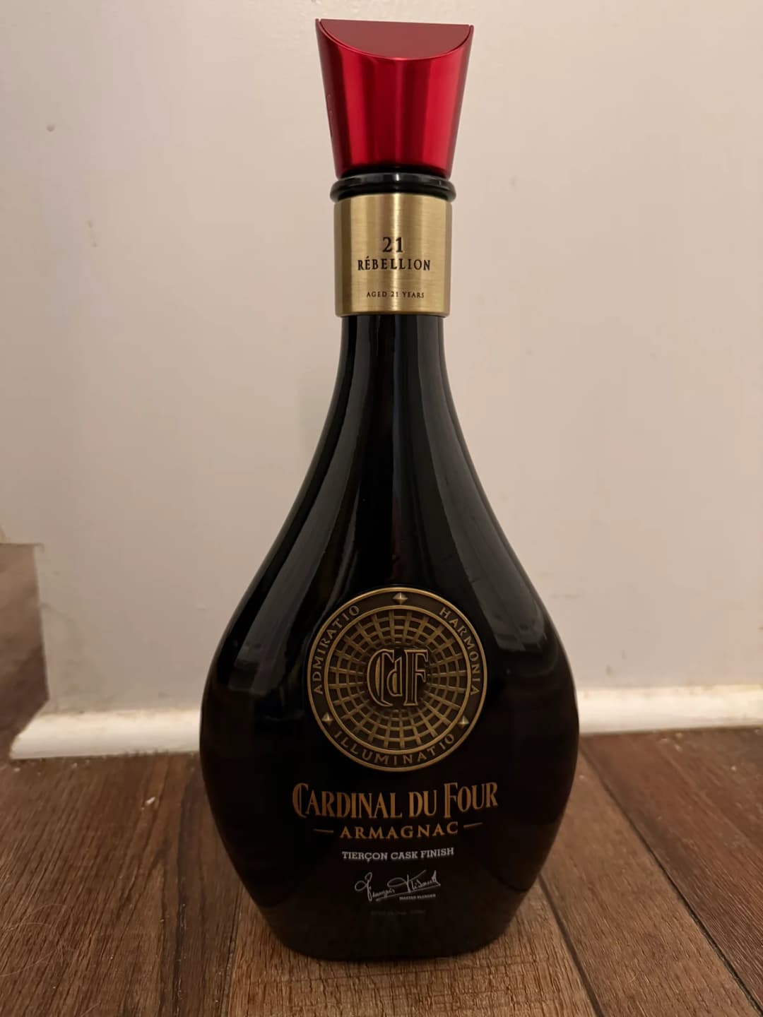 Opaque black Cardinal du Four Armagnac bottle with a red mitre-shaped stopper, a gold 21 Rébellion neck collar and a Tierçon Cask Finish label