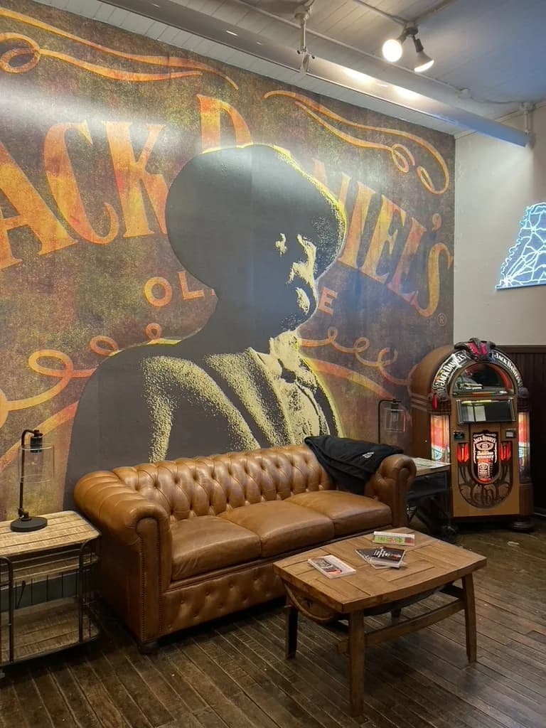 Leather Chesterfield sofa beneath a large mural of Jack Daniel, beside a Jack Daniel's jukebox