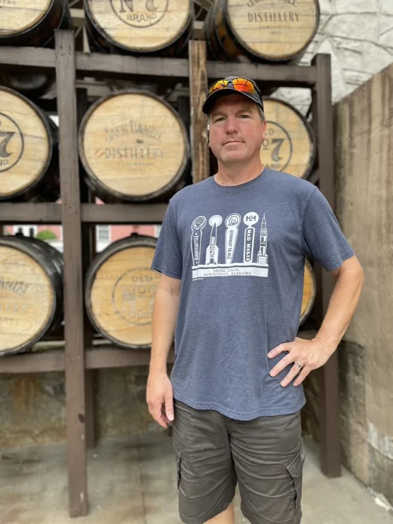 Rob from BoozeMakers standing in front of a rack of Jack Daniel Distillery and Old No. 7 barrel heads in Lynchburg, Tennessee