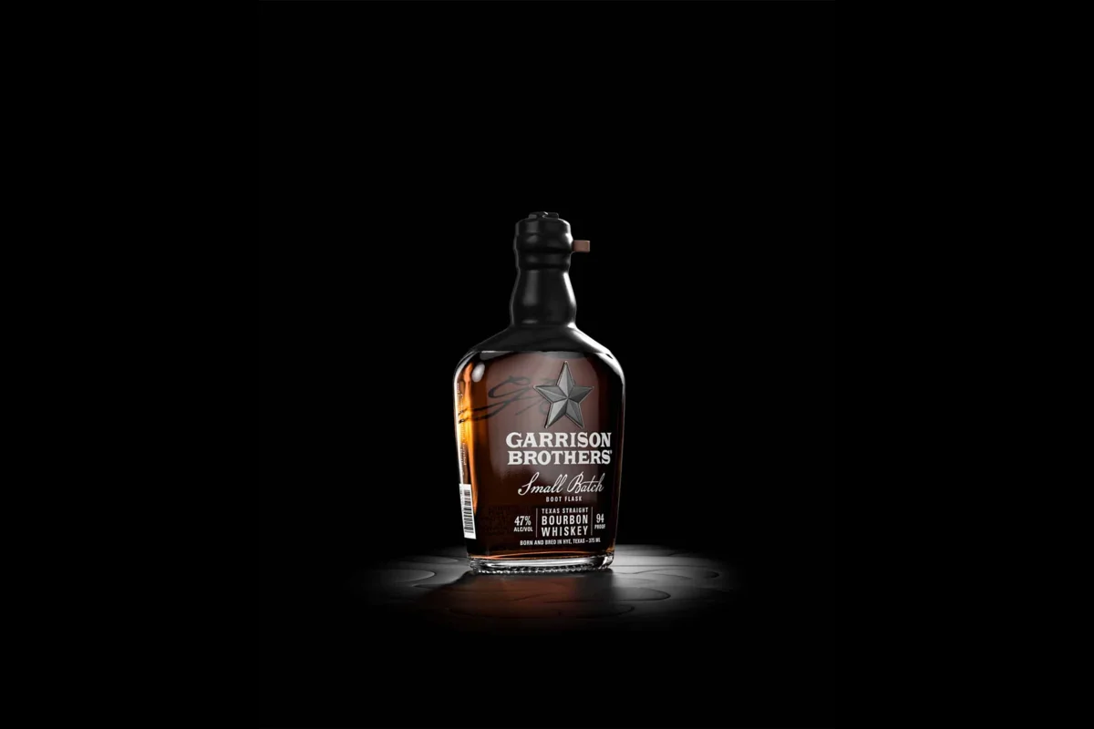 Garrison Brothers Small Batch Boot Flask bottle with a black wax top, spotlit on a black background